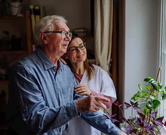 elderly man and carer talking at the window